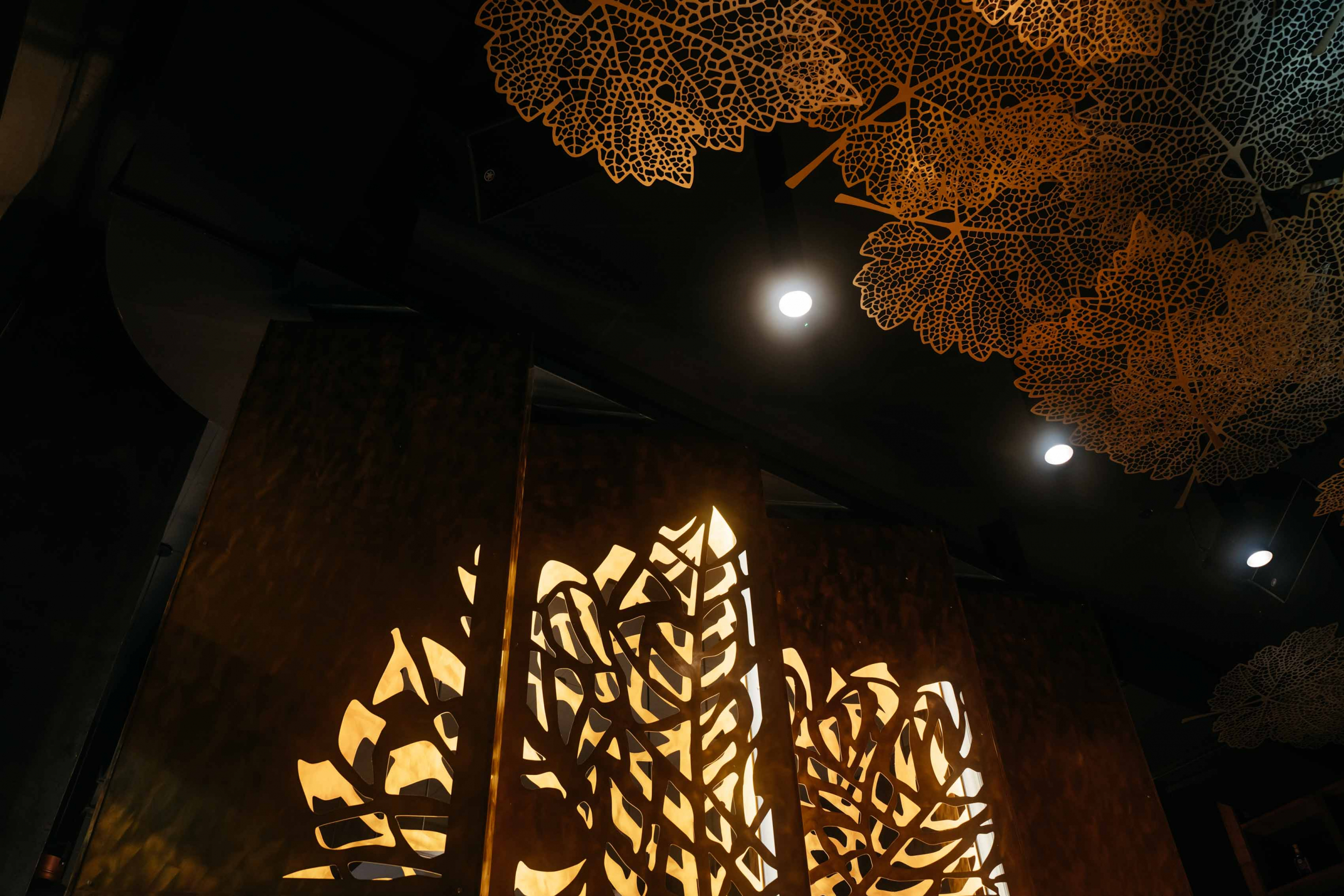 Central focus in restaurant space – Pivot screens made of fine brass material - Illuminating the visual of our Cabernet Sauvignon Leaf.